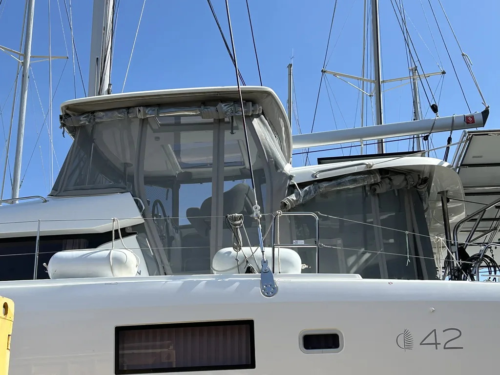 Cockpit enclosure with clear panels fitted over the helm of a catamaran in a boatyard
