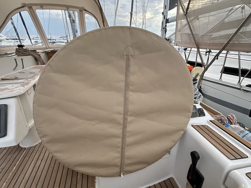 Tan wheel cover on the pedestal of a yacht with a teak deck