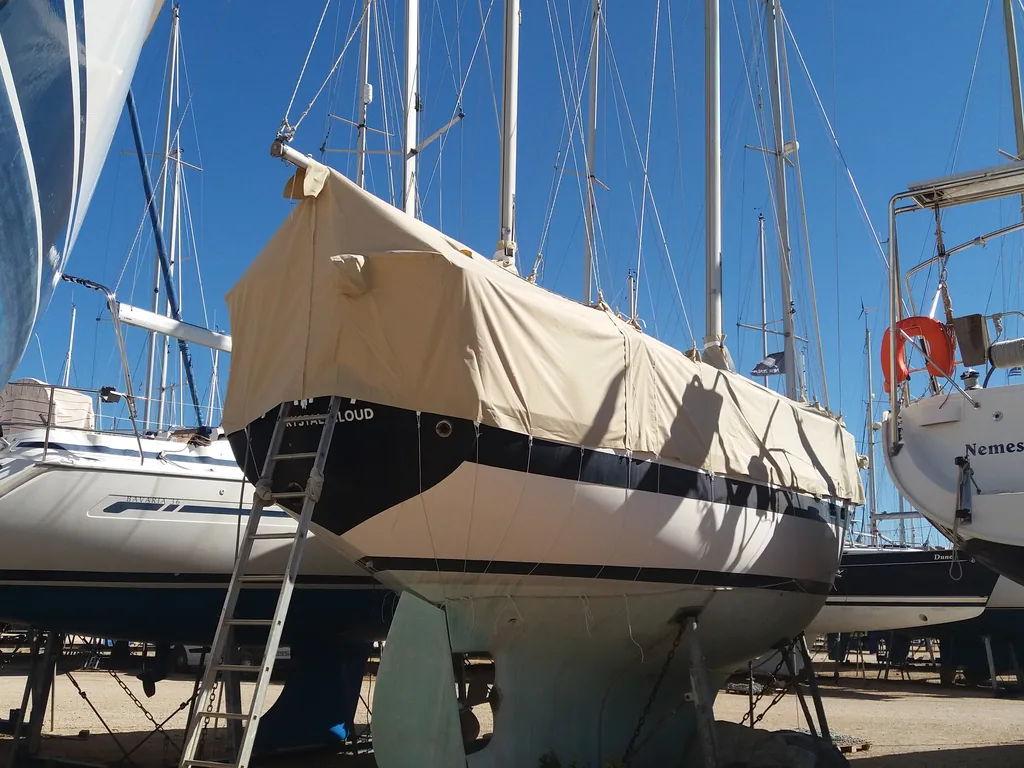 Sailing yacht ashore in the yard under a full tan winter cover