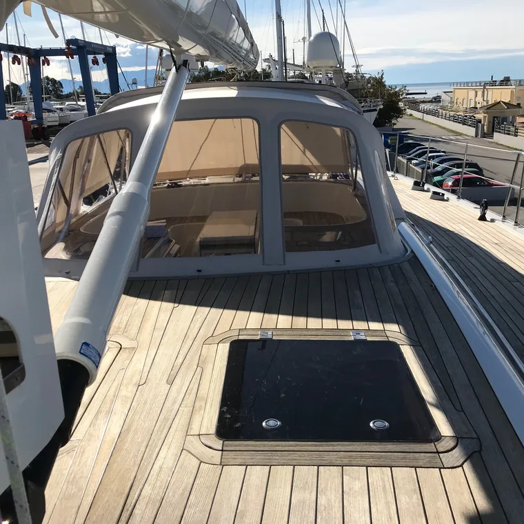 Sprayhood on a wide teak deck, the yard beyond
