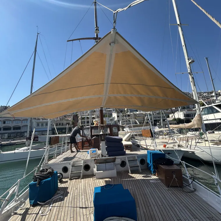 Tan sun awning rigged over the deck of a sailing yacht in a marina