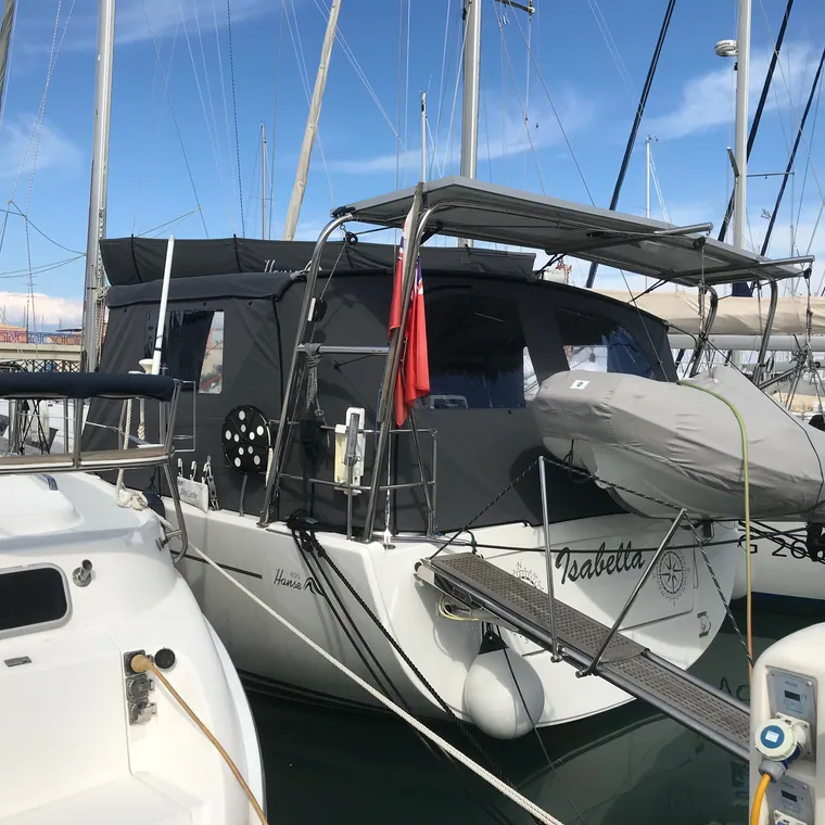 Dark cockpit enclosure fitted along the side deck of a yacht at the dock