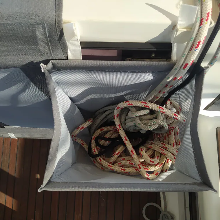 Halyard bag holding coiled lines against a teak coaming