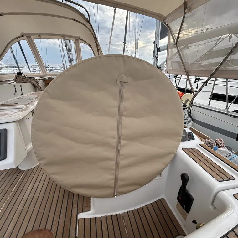 Tan wheel cover on the pedestal of a yacht with a teak deck