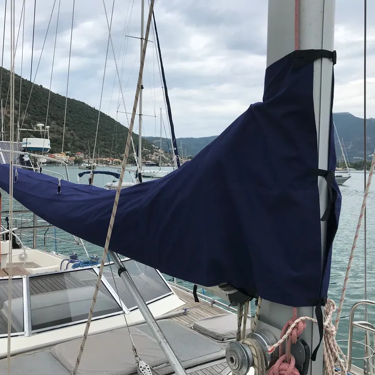 Navy lazy bag zipped shut on the boom, hills behind the marina