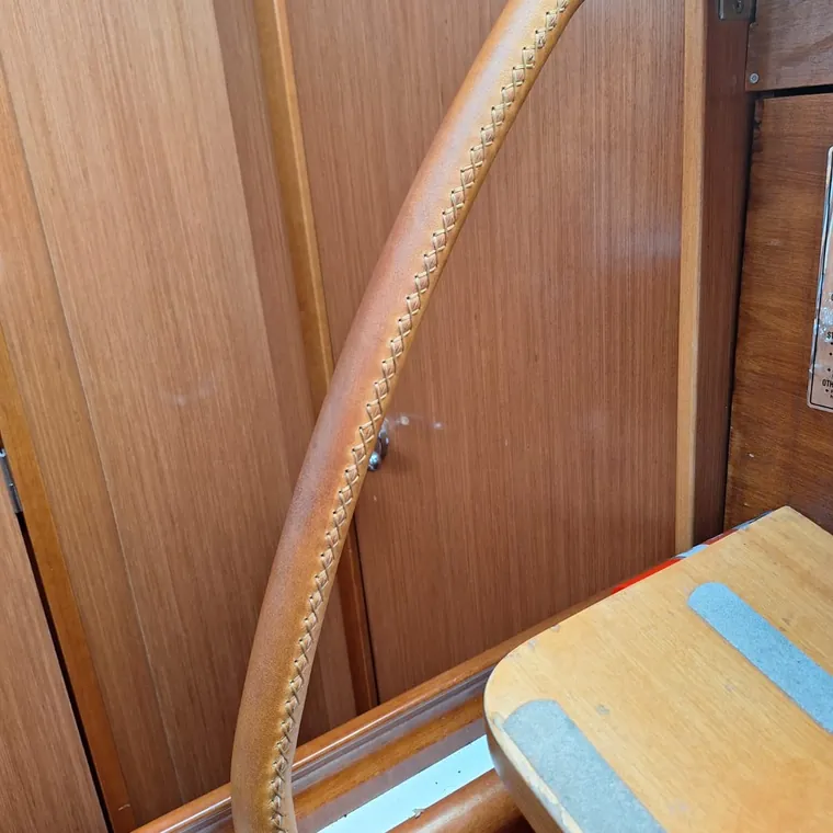 Honey leather stitched over a curved grab rail by the companionway steps