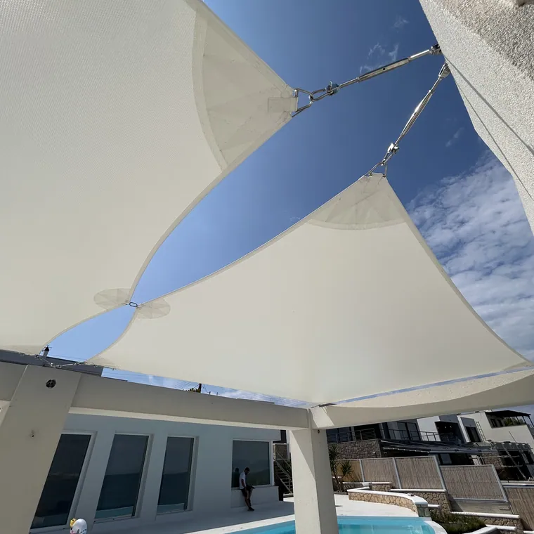 Two white sails overlapping above a pool terrace