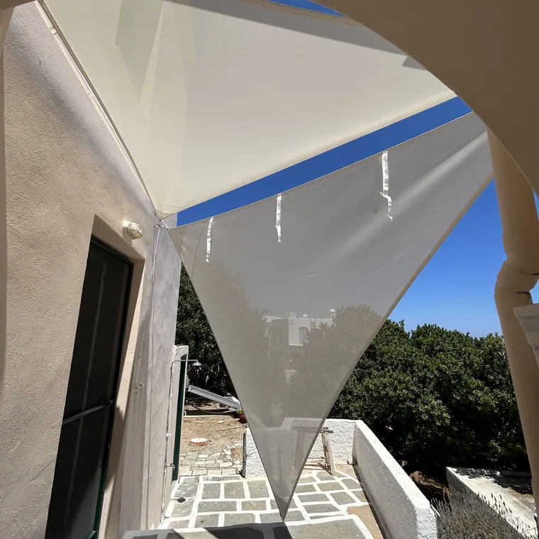 White sail anchored to a wall, shading the side of a house