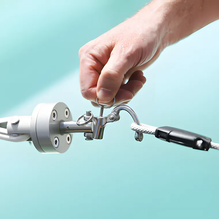 Two hands tightening a stainless turnbuckle at the corner of a sail
