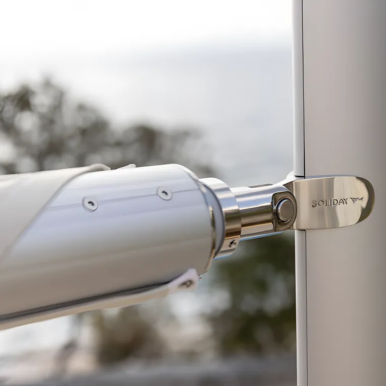 A rolled sail clamped to an aluminium pole with a stainless fitting, the sea behind
