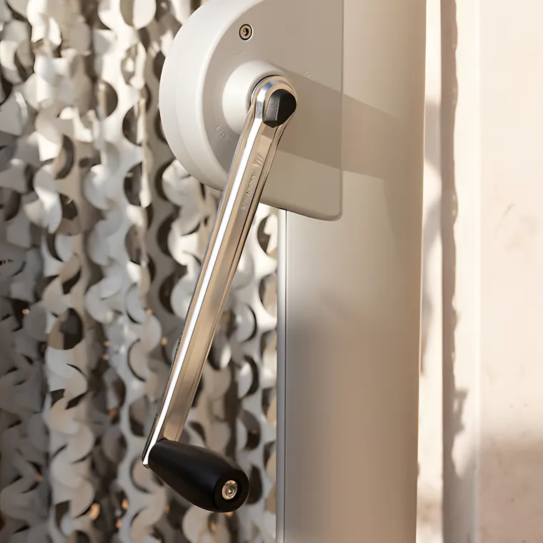 A stainless crank handle on a wall plate, in front of a perforated metal screen