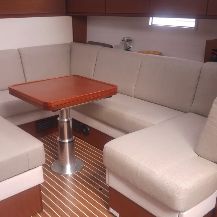 Cream L-shaped saloon settee around a red table below decks