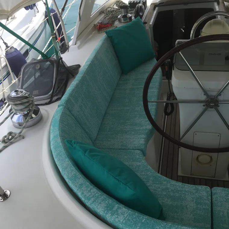 Turquoise cockpit cushions running around the wheel of a sailing yacht