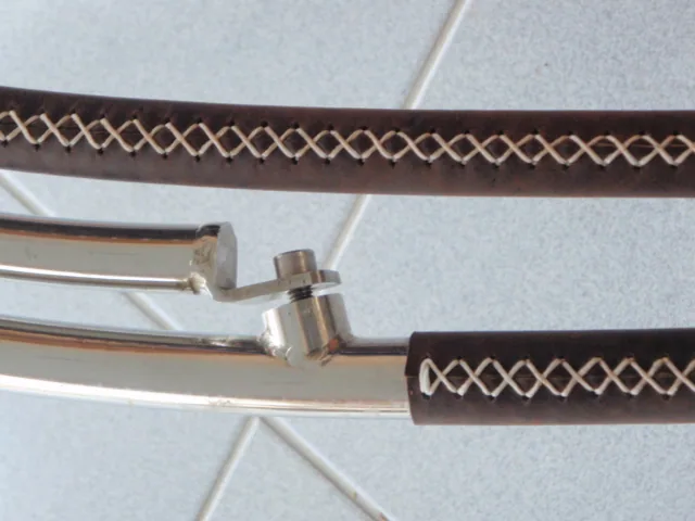 Cross-stitched brown leather grip on a stainless handrail, close up