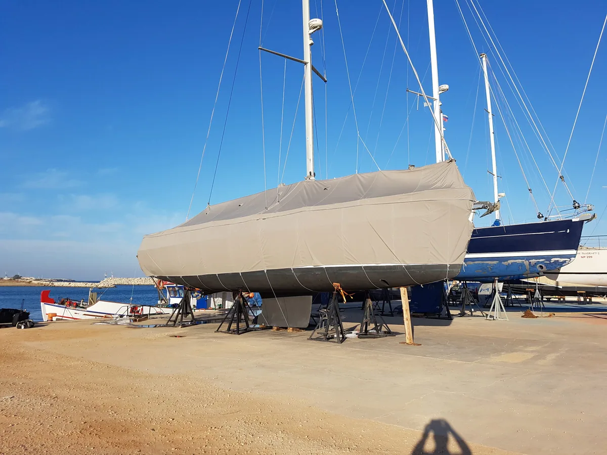 Sailing yacht ashore on the hard under a full grey winter cover
