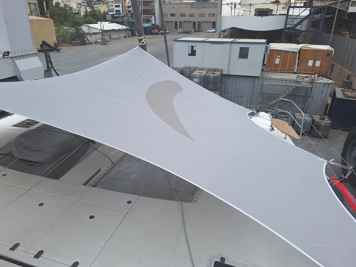 White shade sail tensioned above the deck of a boat in the yard