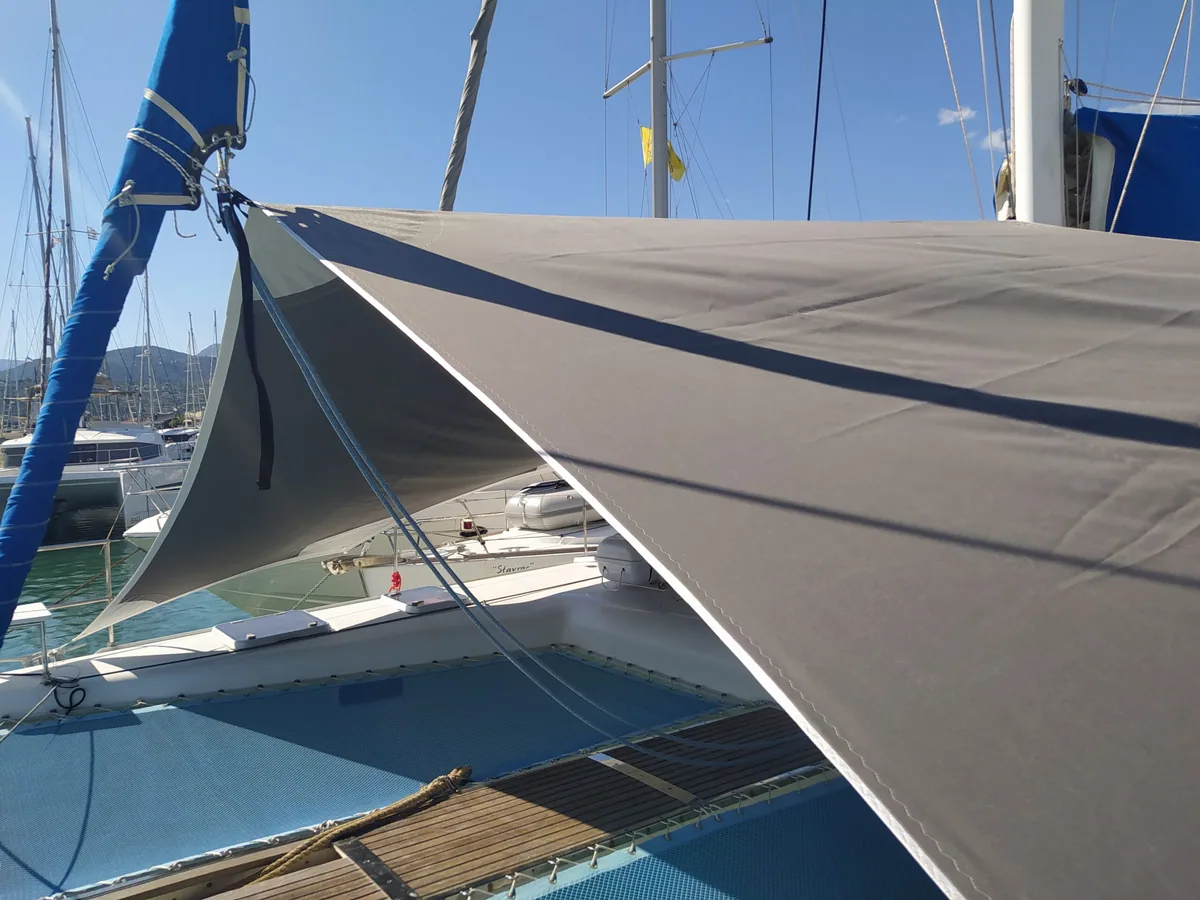Grey shade sail with a blue edge rigged over a yacht in a marina