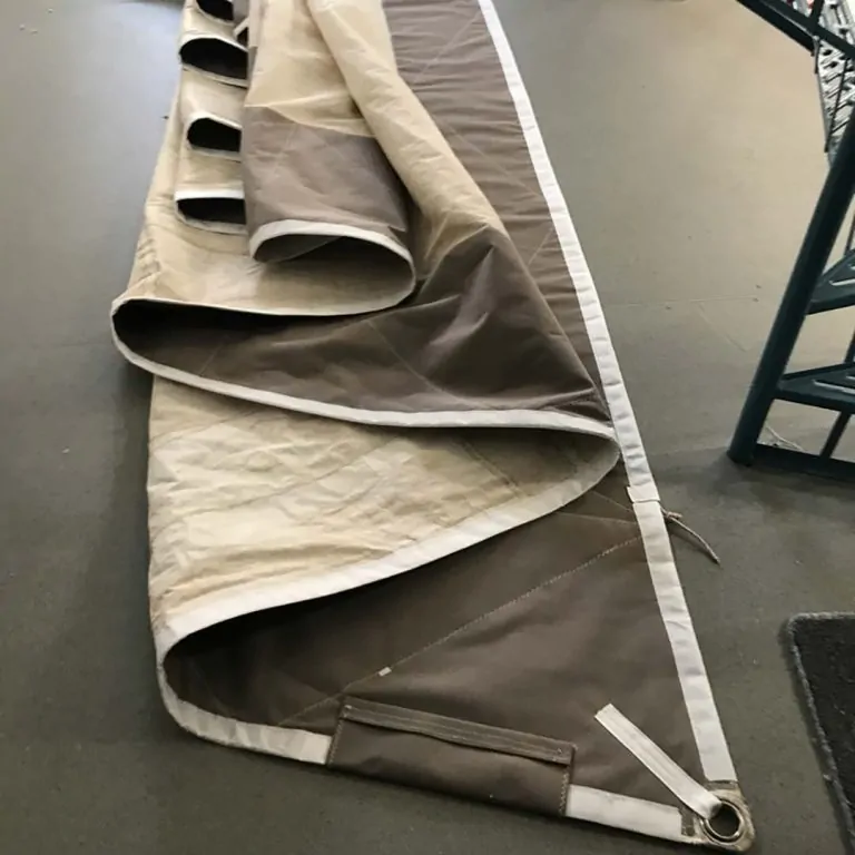 Folded taupe cover with its fittings, resting on a workshop bench